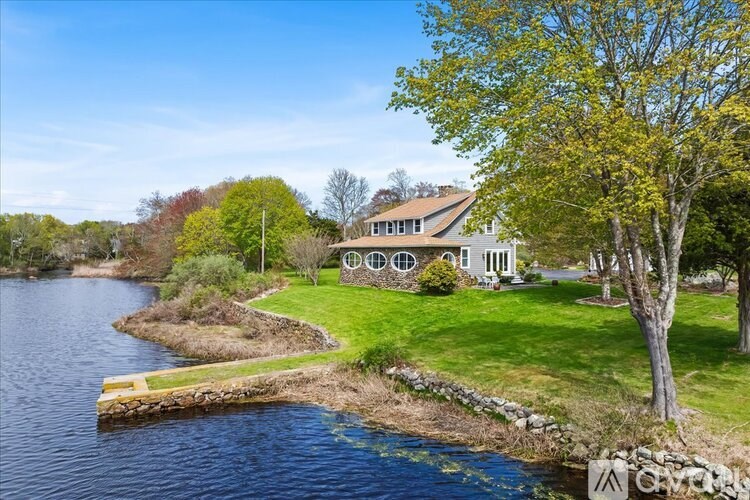 A house is situated by a body of water with a tree in front of it.