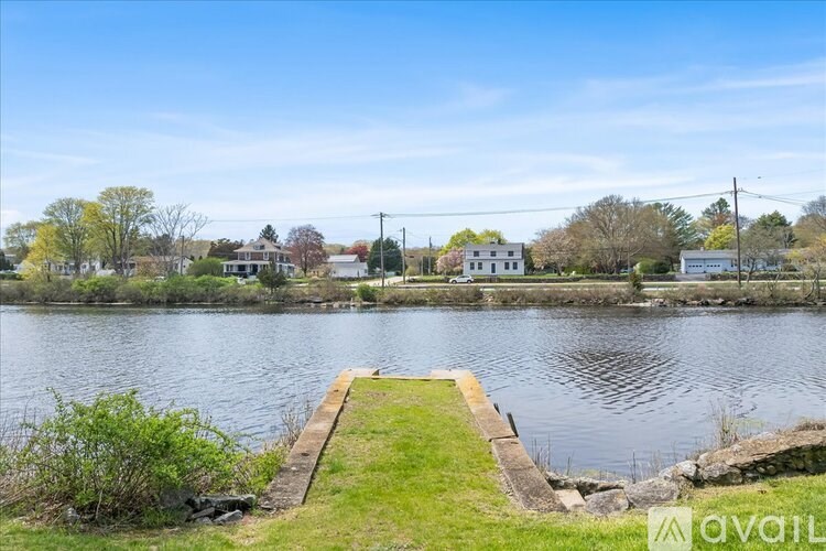 A serene lake with a dock and houses in the background.