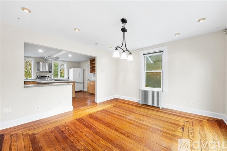 A large empty room with wooden floors and a chandelier.