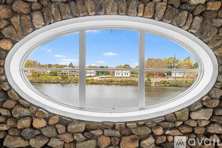 A window with a stone wall and a view of a lake and houses.