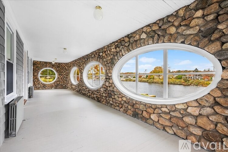 A room with a stone wall and three round windows.