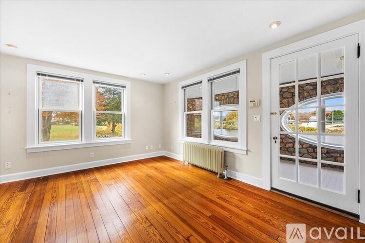 A room with wooden floors and a view of a garden through the windows.