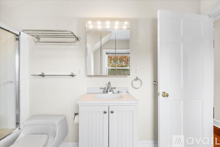 A white bathroom with a toilet, sink, and mirror.