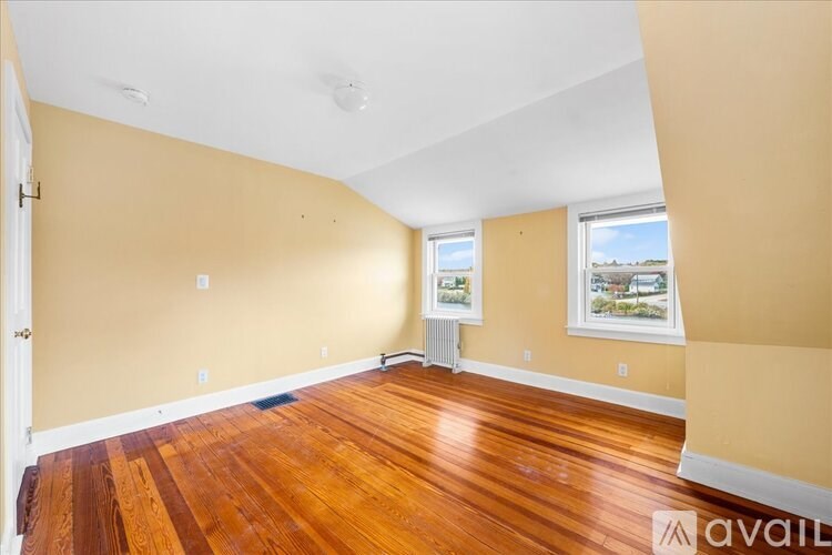 A room with wooden floors and two windows.