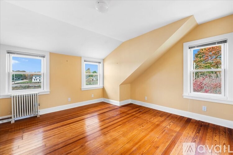A room with wooden floors and two windows.