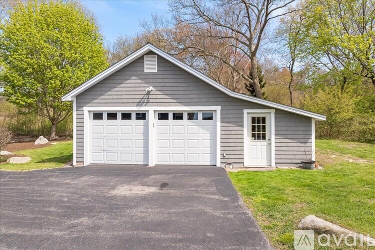 A two-car garage with a grey roof and white doors is surrounded by a driveway and green grass.