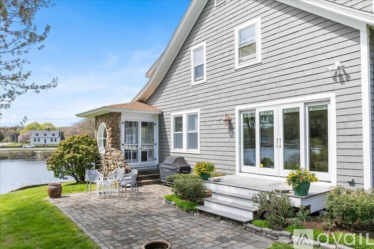A house with a grey siding exterior and a patio area with chairs and a table.