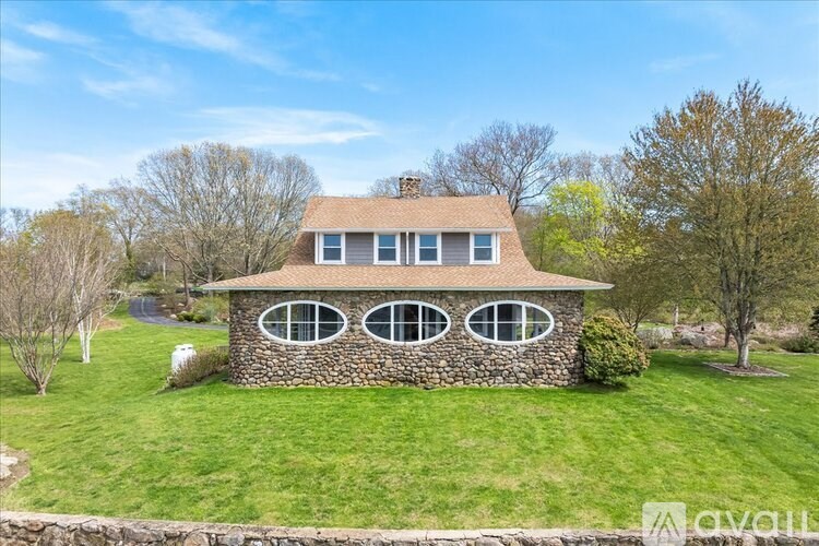 A stone house with a brown roof and four windows.