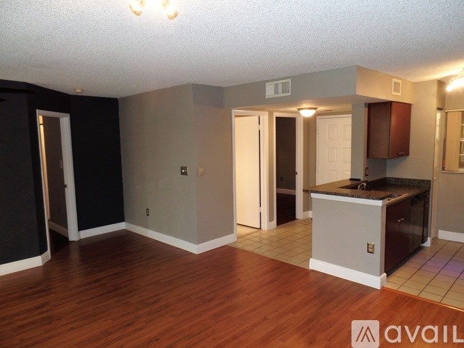 A room with a wooden floor and a kitchenette.