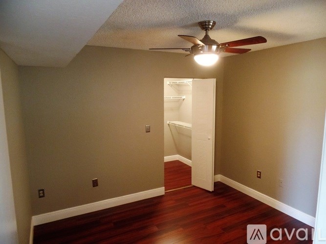 A room with a ceiling fan and a doorway leading to another room.