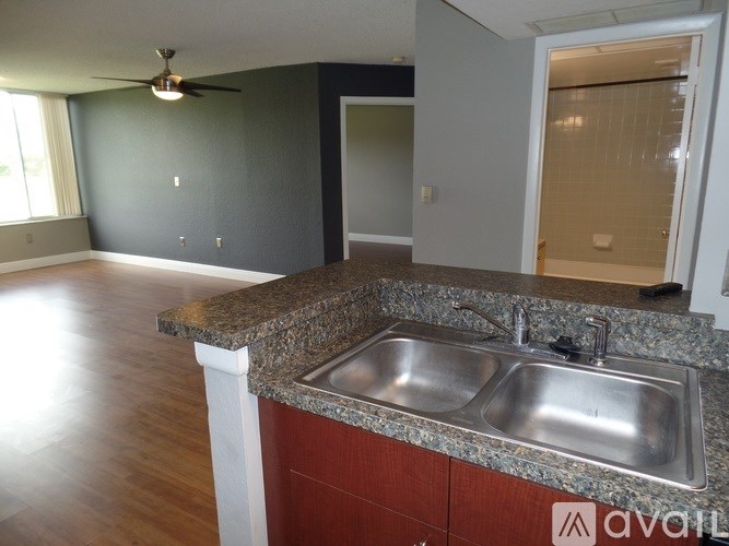 A kitchen with a marble countertop and a stainless steel sink.