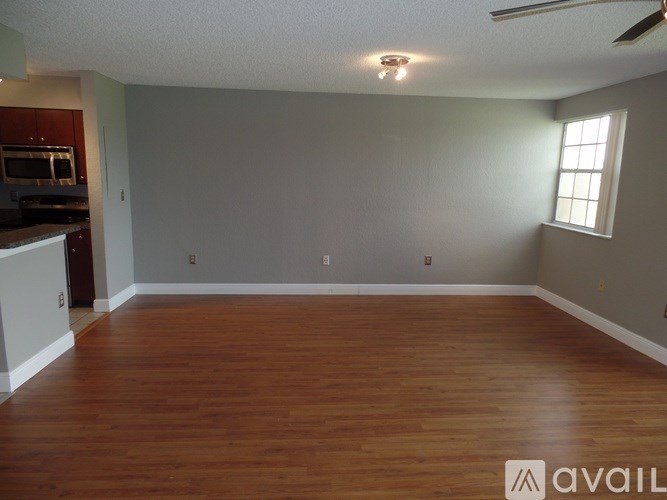 A room with wooden floors and a window on the right side.