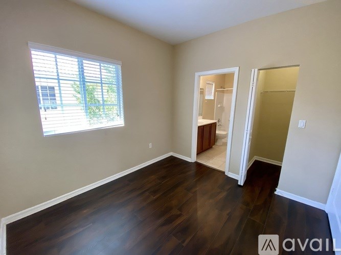 A room with wooden floors and a window with blinds.