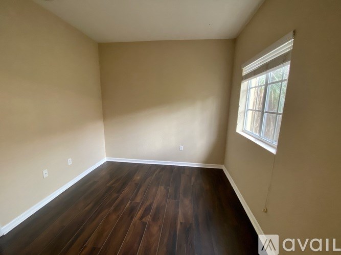 A room with wooden floors and a window letting in natural light.