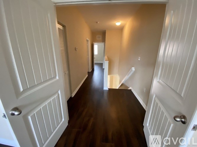 A long hallway with white doors and wooden floors.