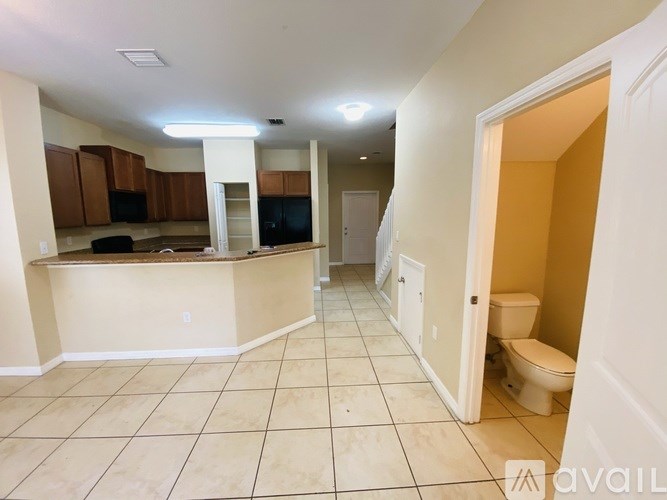 A spacious kitchen and living room area with tiled flooring and a bar area.