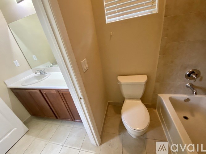 A white toilet sits in a bathroom next to a bathtub.