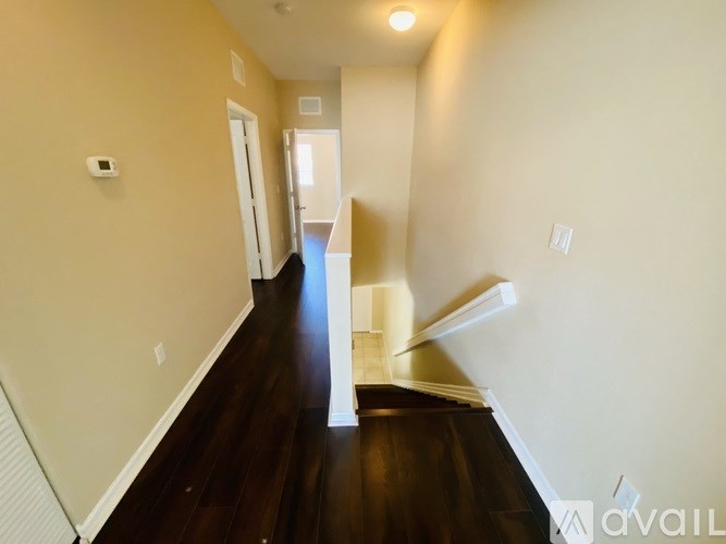 A hallway with wooden floors and white walls.