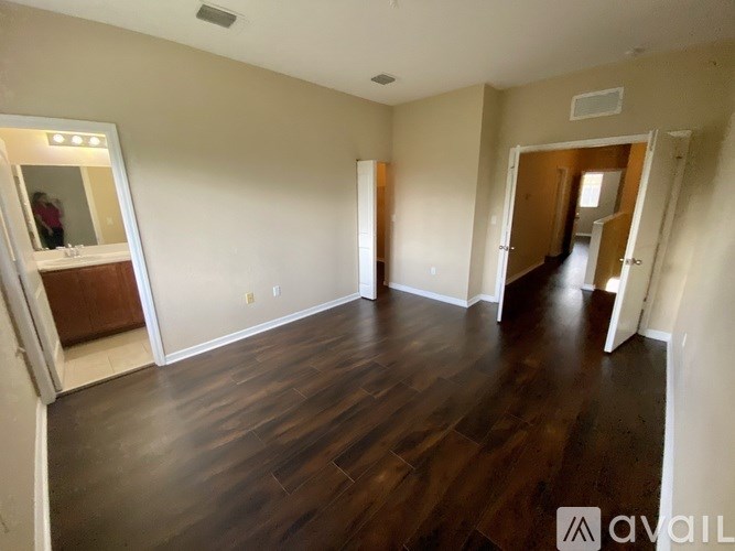 A spacious room with wood flooring and white walls.