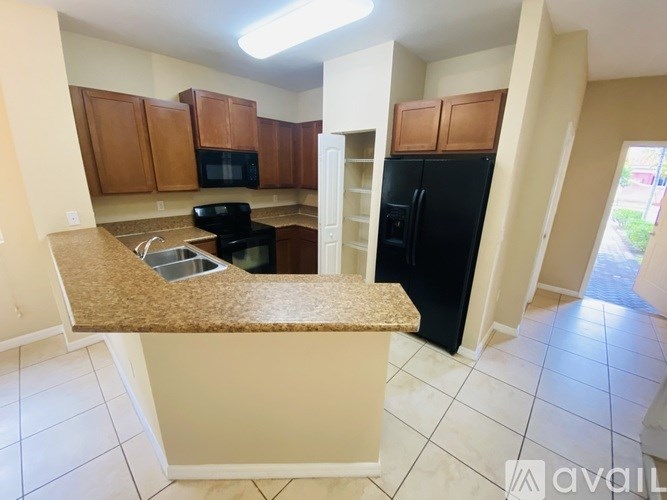A kitchen with black appliances and brown cabinets.