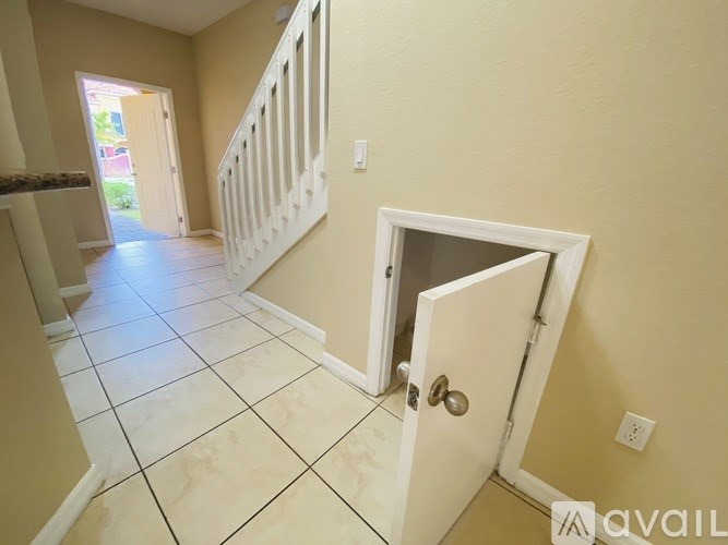 A hallway with a white door and a white staircase.