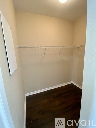 A small, empty room with a wooden floor and a white door.