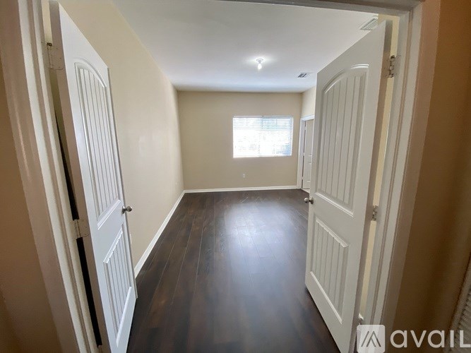 A hallway with white doors and a wooden floor.