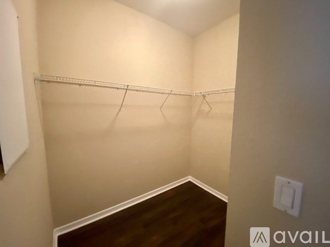 A small, empty room with a wooden floor and a white wall.