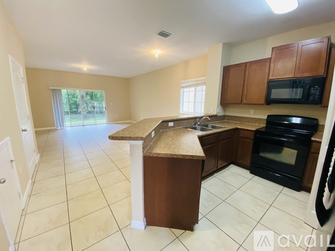 A kitchen with brown cabinets and black appliances.