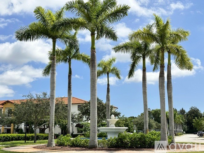 A row of palm trees in front of a building with a fountain.