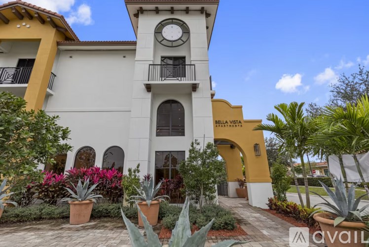 A white building with a yellow arch and a clock on the front.