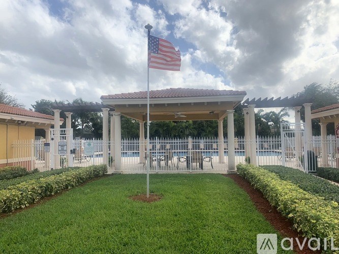 A gazebo with an American flag on top is surrounded by a well-manicured lawn.