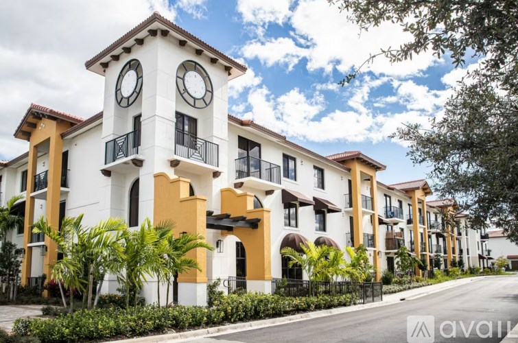 A row of white and yellow buildings with balconies and a clock tower.