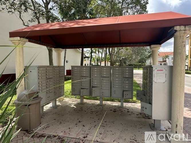 A row of mailboxes are lined up under a red roof.