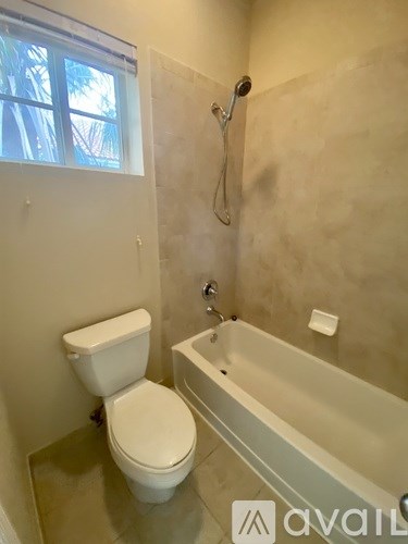 A bathroom with a toilet, tub, and window.