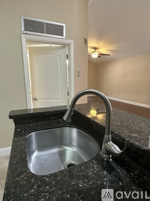 A kitchen sink with a faucet and a black countertop.