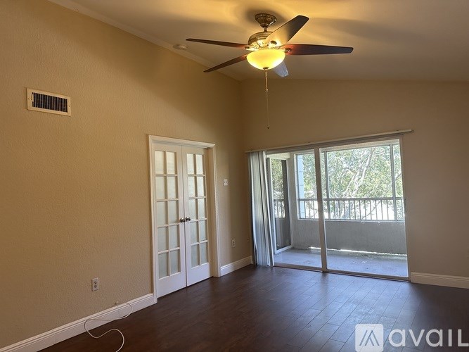 A room with a ceiling fan and sliding glass doors.