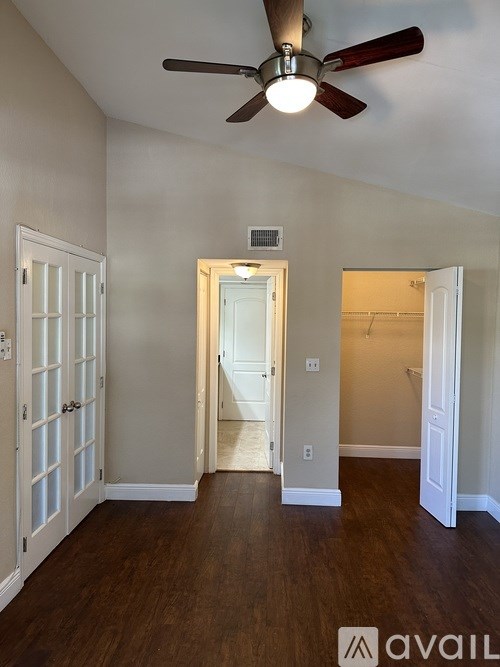 A room with a ceiling fan and wooden floors.