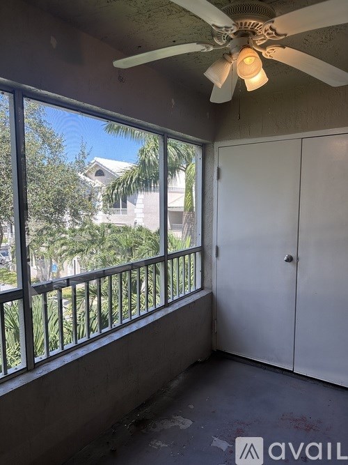 A room with a ceiling fan and a window overlooking a balcony.