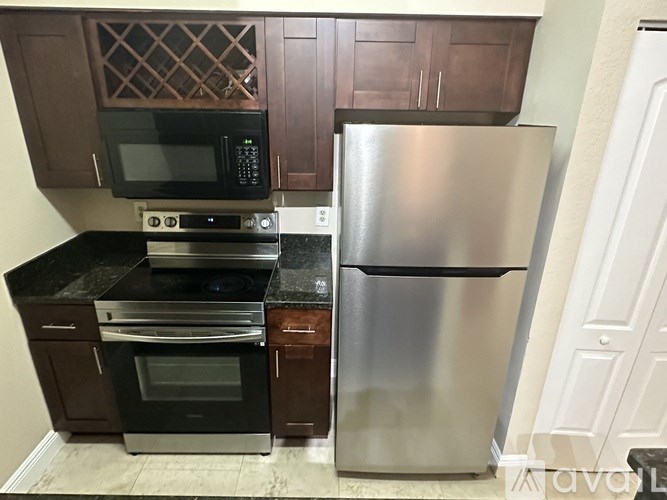 A kitchen with a stainless steel refrigerator and black countertops.