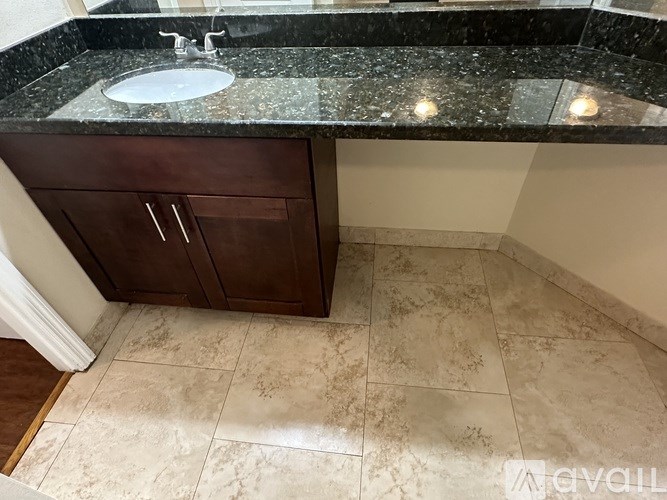 A bathroom with a sink, a cabinet, and a tiled floor.