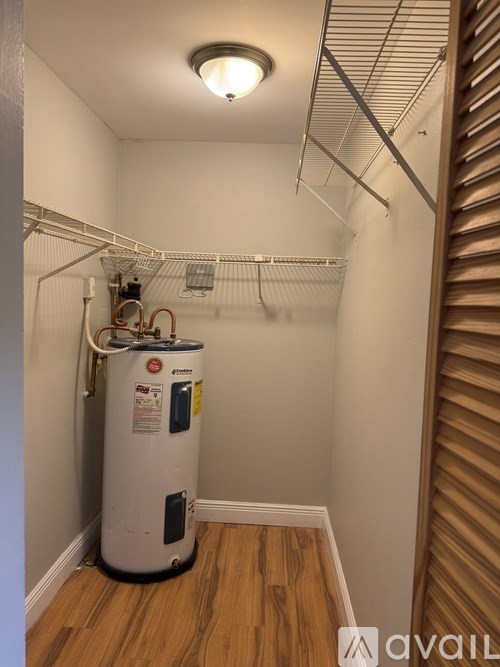 A room with a water heater and a light on the ceiling.