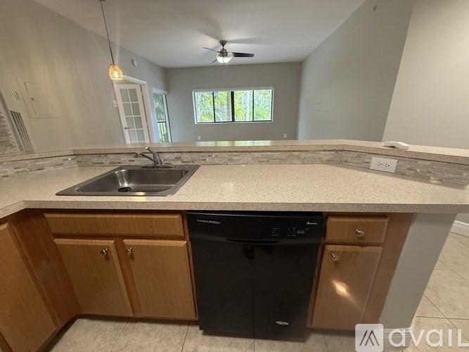 A kitchen with a black dishwasher and wooden cabinets.