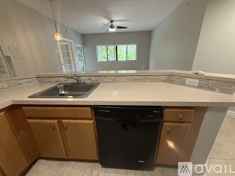 A kitchen with a black dishwasher and wooden cabinets.
