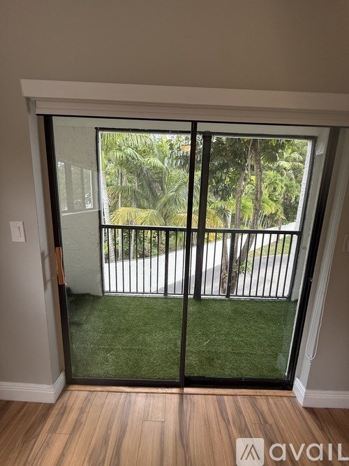 A patio door with a view of a green lawn and trees.