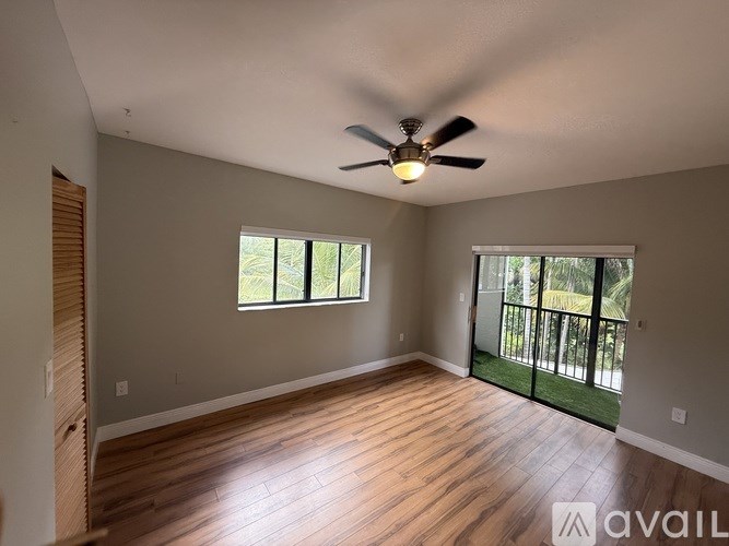 A room with a ceiling fan and sliding glass doors.