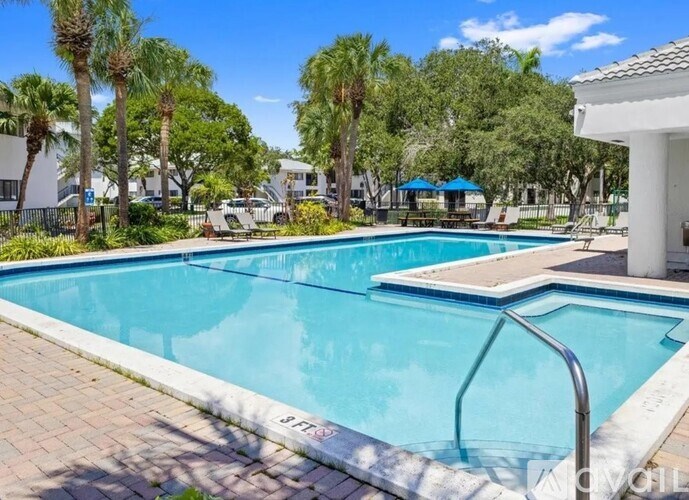 A swimming pool surrounded by palm trees and a white building.