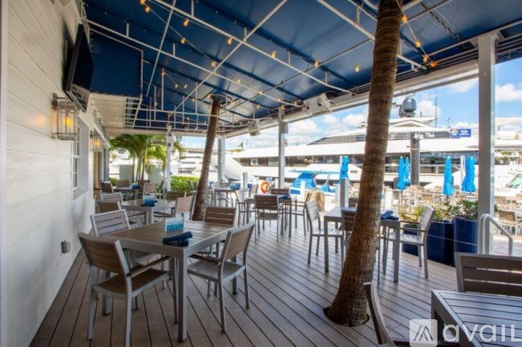 A wooden deck with chairs and a table under a blue canopy.