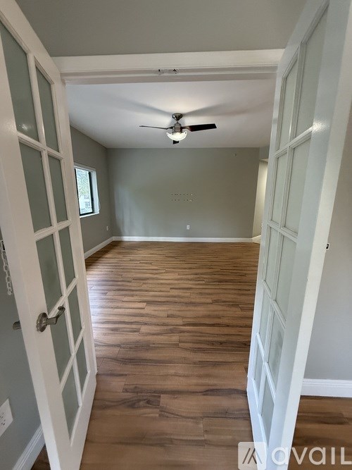 A room with a ceiling fan and wood flooring.