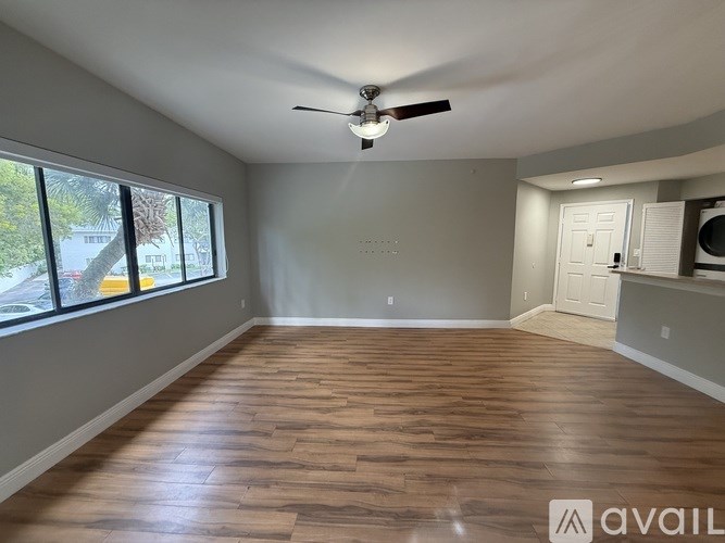 A spacious room with wooden flooring and a ceiling fan.